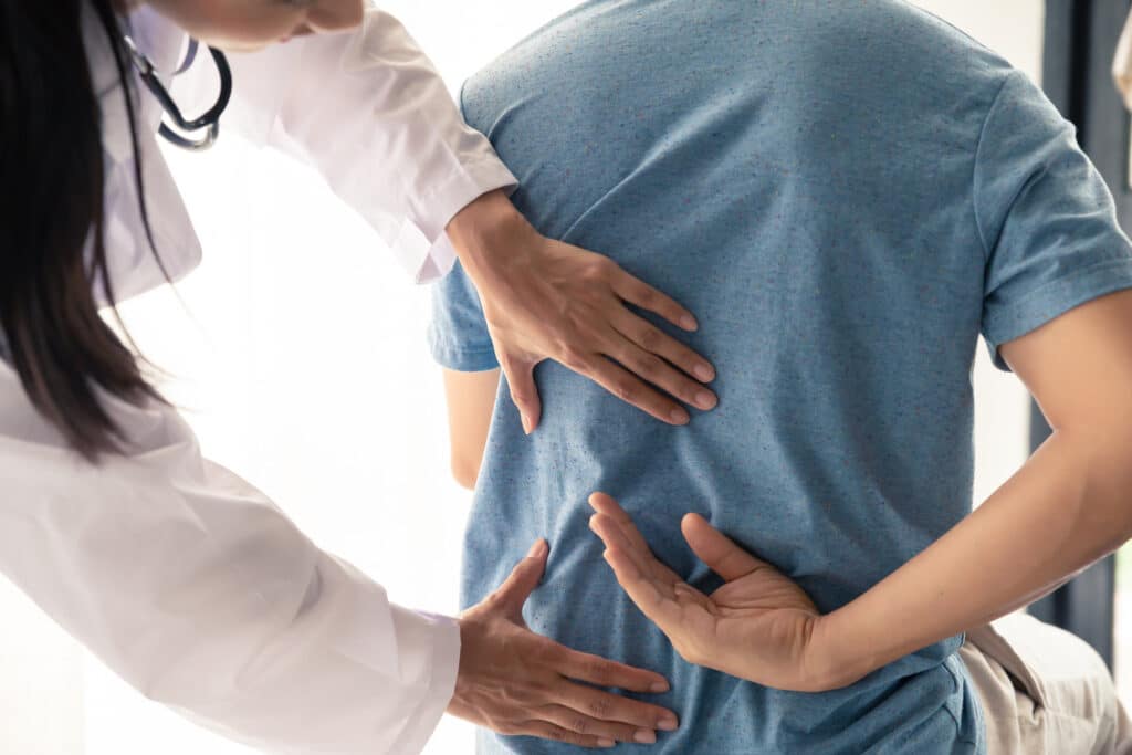 Physiotherapist treating back pain to male patient