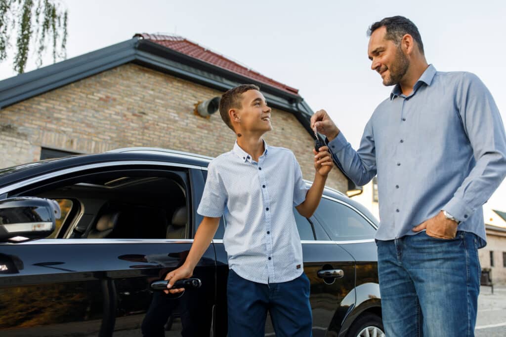 A father giving car keys to his teenage son