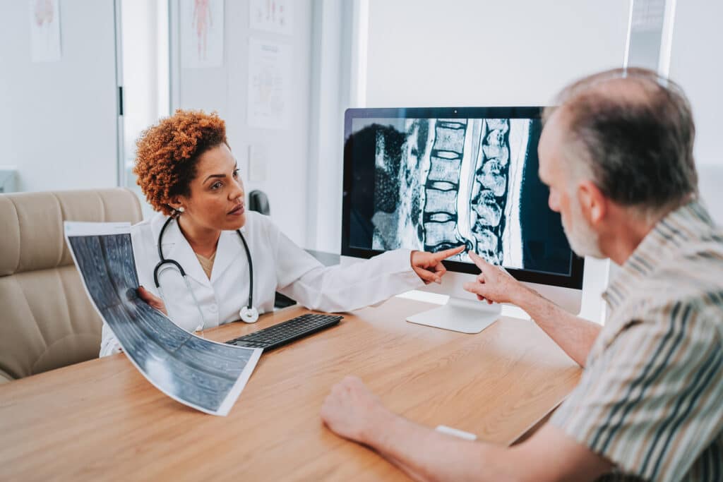 Medical visit, MRI of the spine showing a herniated disc, doctor talking with an elderly patient